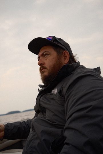Josh LeClair out on the water in a ball cap and rain jacket