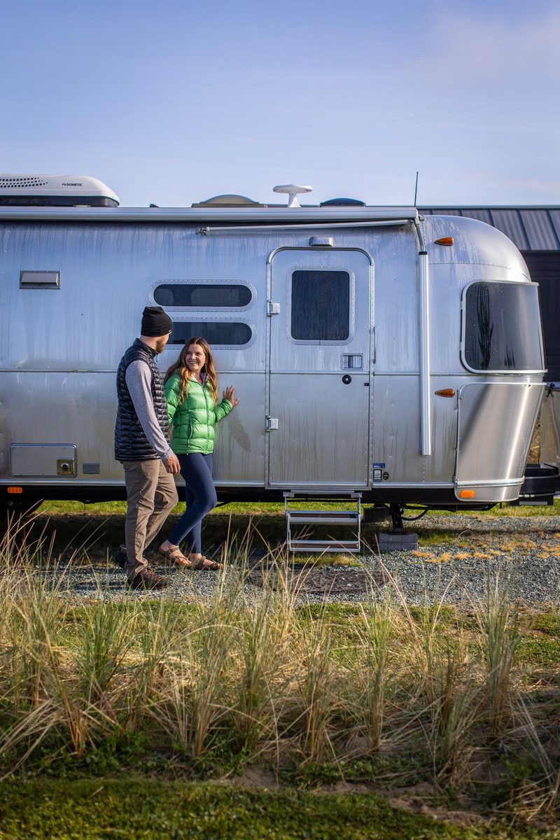 Couple with an Airstream trailer at a waterfront campground