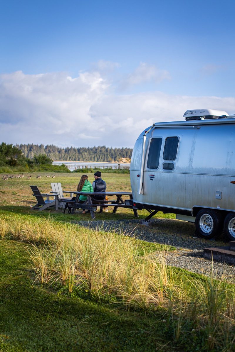 Couple with an Airstream trailer at a waterfront campground