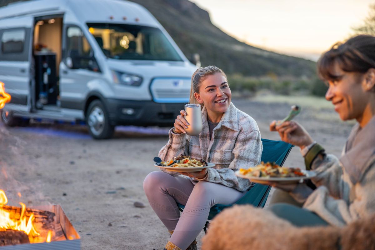 Campfire at sunset beside a camper van