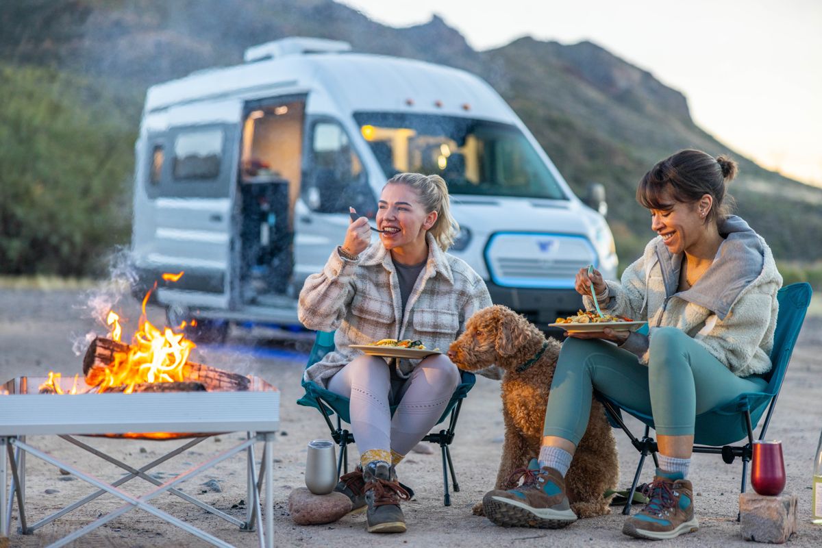 Friends around a desert campfire with their van