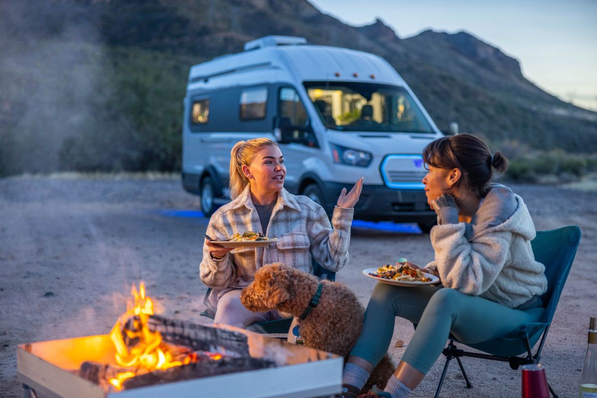 Evening campfire beside a camper van in the mountains