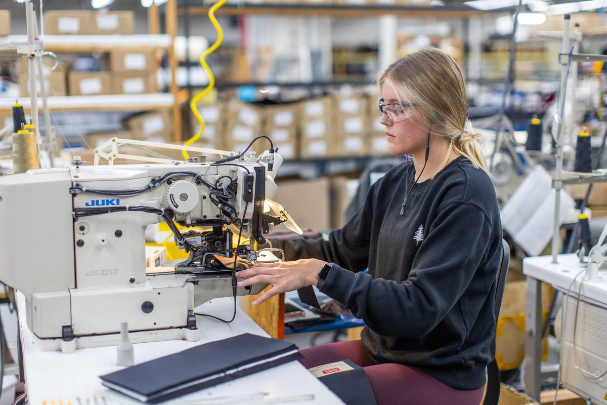 Workers sewing and finishing outdoor apparel on a factory floor
