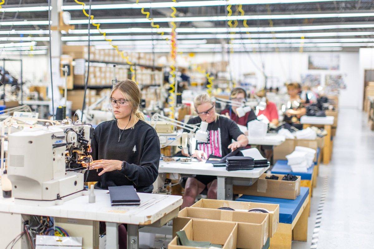 Workers sewing and finishing outdoor apparel on a factory floor